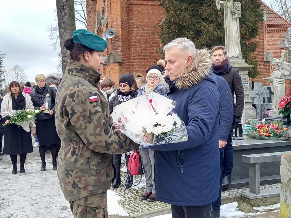 Cmentarz, Przewodniczący rady Powiatu Plońskiego podaje żołnierzowi wiązankę patriotycznych kwiatów..jpg