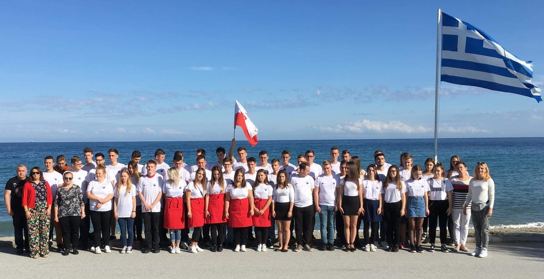 Zdjęcie przedstawia uczniów na tle morza z Polską i Grecką flagą.