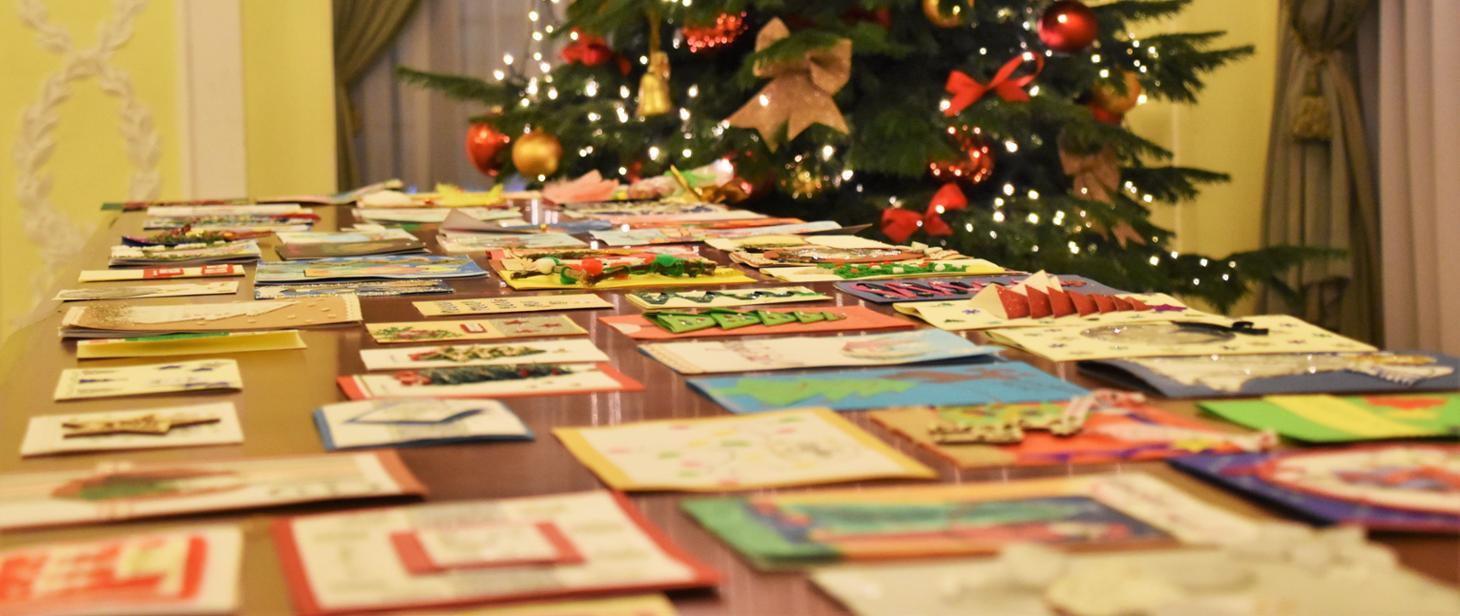 kartki świąteczne ułożone na stole w tle udekorowana choinka.jpg