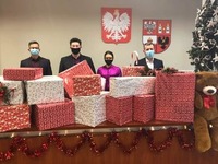 Zarząd powiatu płońskiego stoi za ułożonymi spakowanymi prezentami dla szlachetnej paczki.jpg
