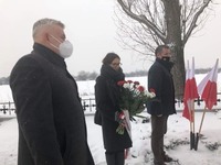 Starosta z kwiatami wraz z Wicestarostą i Przewodniczącym Rady Powiatu stoją na ośnieżonej ziemi w tle stoją polskie flagi.jpg