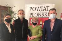 Starosta Wicestarosta i członkowie Związku Emerytów, Rencistów i w Płońsku stoją przed rollupem Powiatu Płońskiego.jpg