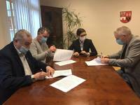 Starosta i Wicestarosta siedzą przy stole i podpisują umowę z przedstawicielamiMKS BANK BS Płońsk.jpg