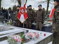 żołnierze z flagą stoją nad symbolicznym grobem poległych w Powstaniu Styczniowym.
