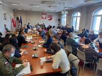 Zaproszeni goście siedzą na sali konferencyjnej podczas posiedzenia Powiatowego Zespołu Zarządzania Kryzysowego