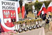 Puchary i medale dla zwycięzców biegu w tle rollup powiatu i flagi państwowe