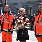 Dyrektor Szpitala w Płońsku Liliana Kraśniewska oraz dwaj ratownicy medyczni składają kwiaty przy pomniku Konstytucji Trzeciego Maja.