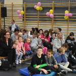 Uczestnicy Powiatowego Dnia Dziecka siedzą na sali gimnastycznej. 
