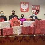 Zarząd powiatu płońskiego stoi za ułożonymi spakowanymi prezentami dla szlachetnej paczki.jpg
