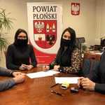 Starosta i Wicestarosta oraz przedstawiciele Uczniowskiego Klubu Sportowego Maksymilian w Płońsku siedzą przy stole w gabinecie Starosty i podpisują umowę