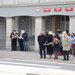 Uczestnicy uroczystości trzeciomajowych stoją z kwiatami przed budynkiem starostwa